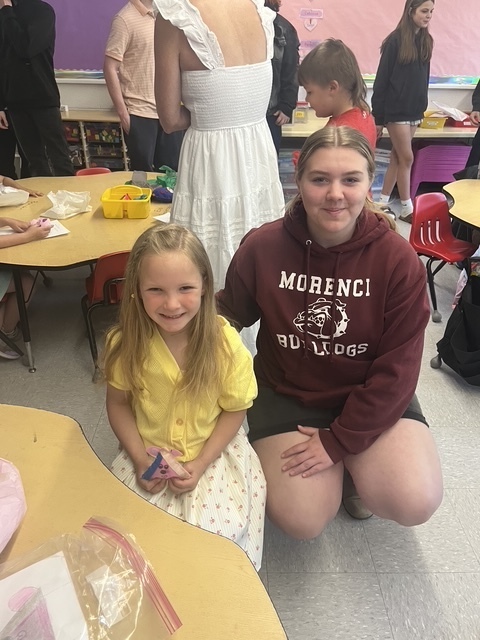 Kindergarten and 8th grade student posing for picture with the stuffed animal that was made for them.