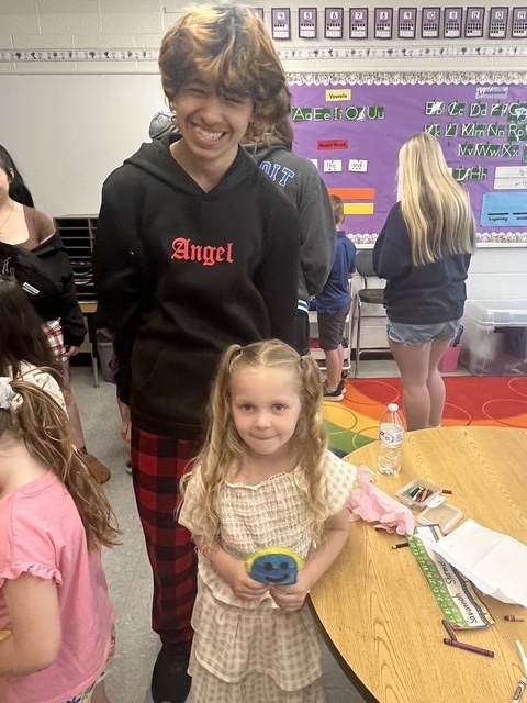 Kindergarten and 8th grade student posing for picture with the stuffed animal that was made for them.