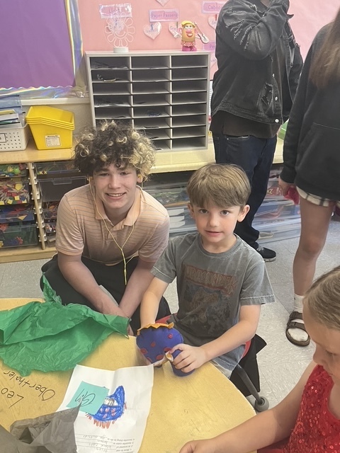Kindergarten and 8th grade student posing for picture with the stuffed animal that was made for them.