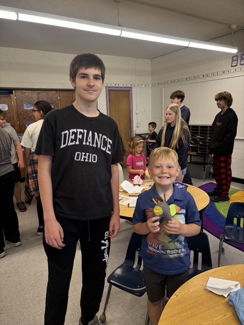 Kindergarten and 8th grade student posing for picture with the stuffed animal that was made for them.
