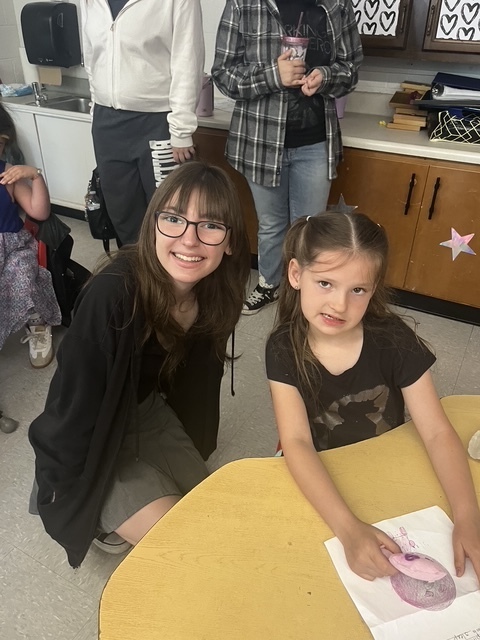 Kindergarten and 8th grade student posing for picture with the stuffed animal that was made for them.
