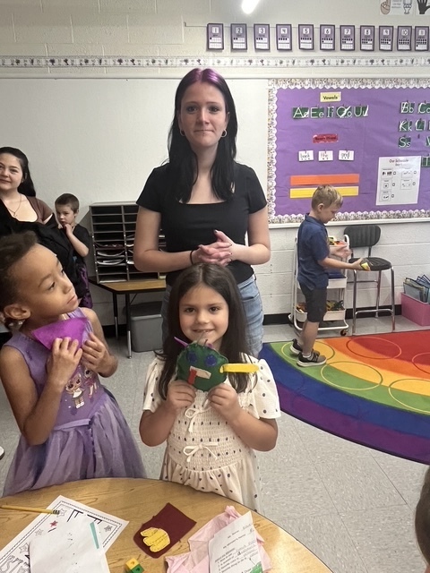 Kindergarten and 8th grade student posing for picture with the stuffed animal that was made for them.