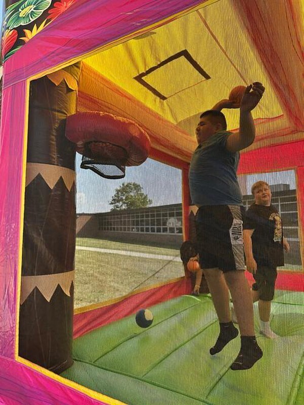 student shooting basket in bounce house