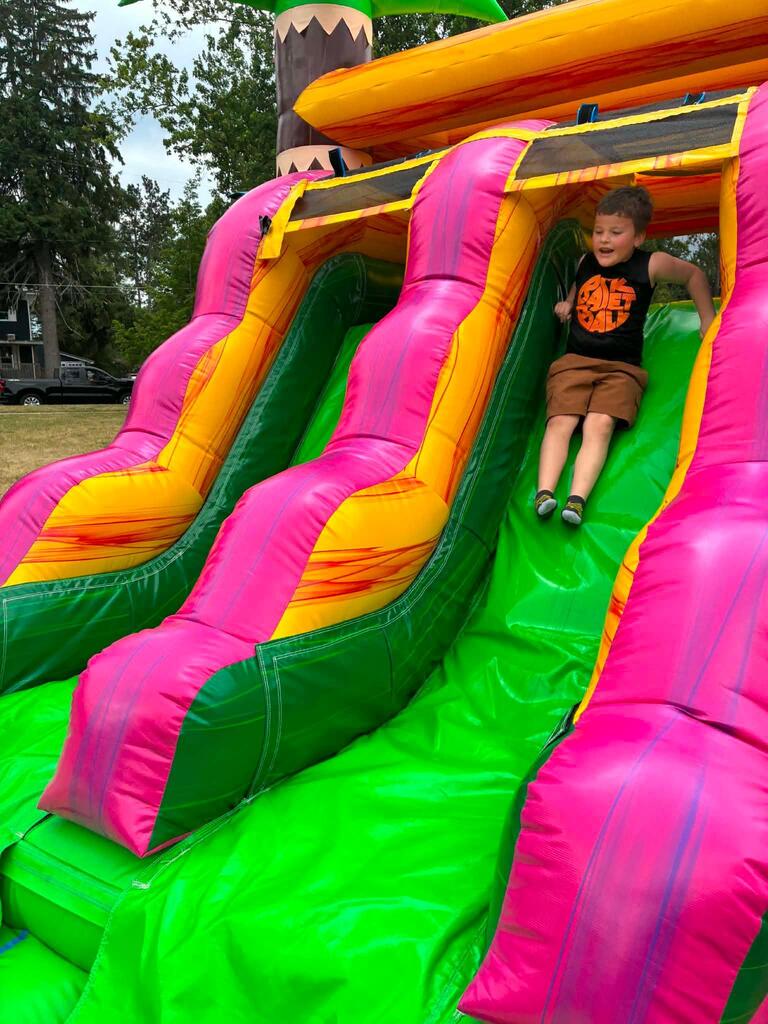 student sliding down bounce house slide