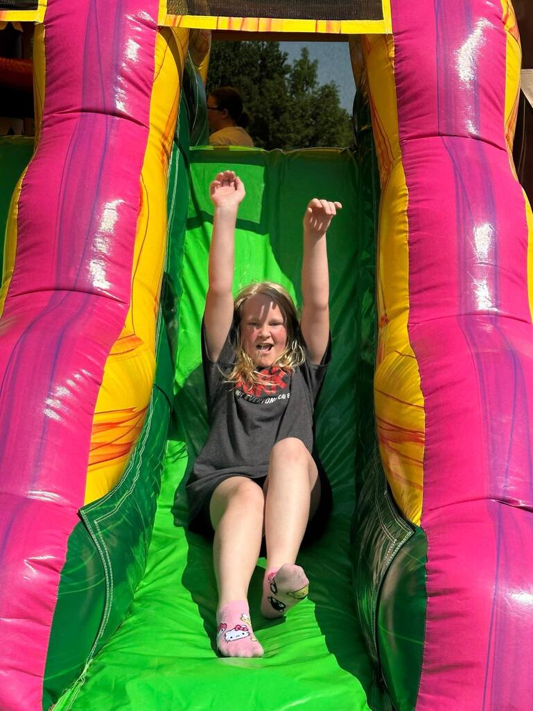 student sliding down bounce house slide