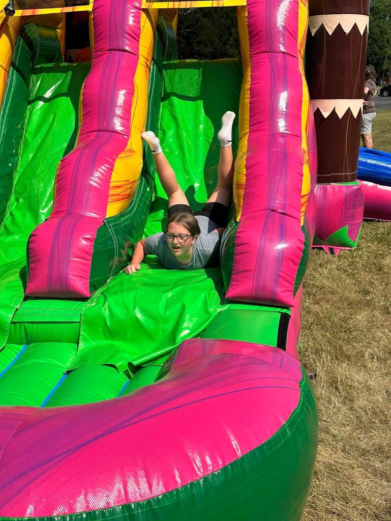 student sliding down bounce house slide