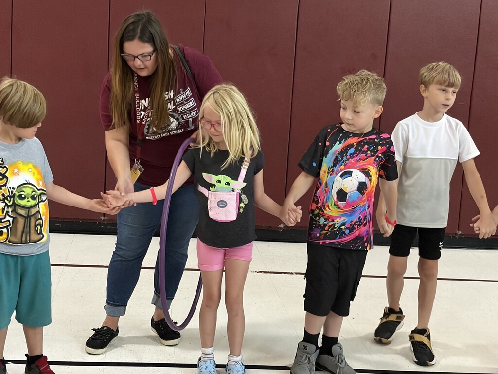 students holding hands and passing a hula hoop