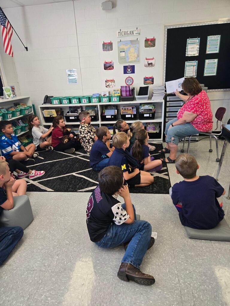 adult reading a book to students