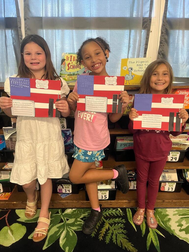 three students holding a flag project