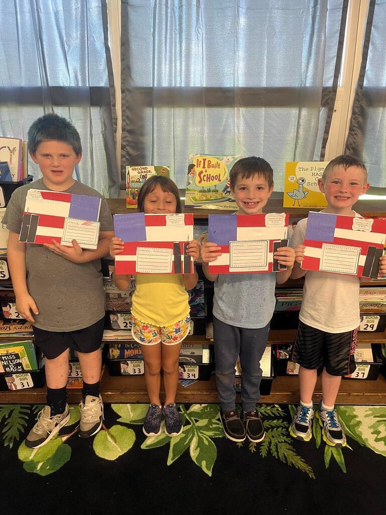 four students holding a flag art project they did in class.