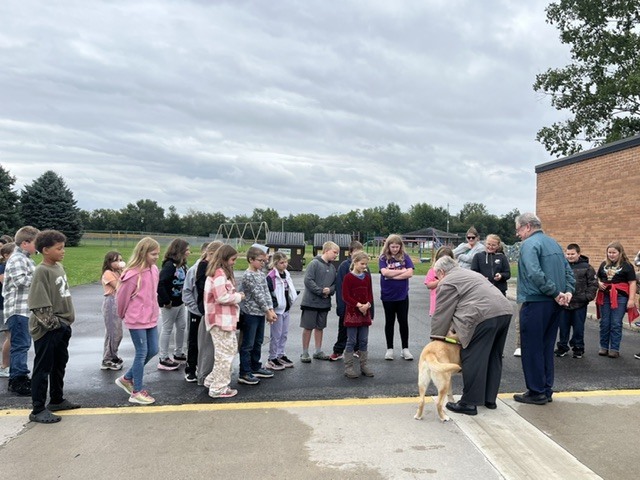 blind man showing his service dog to students