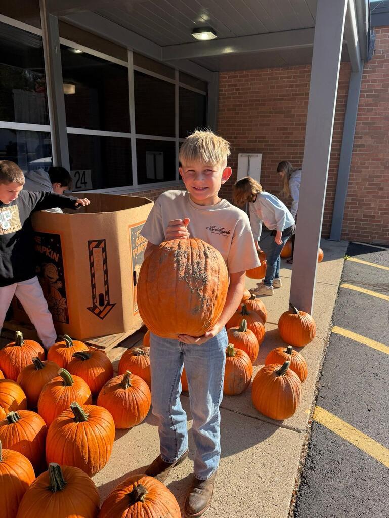 student holding pumpkin he picked out