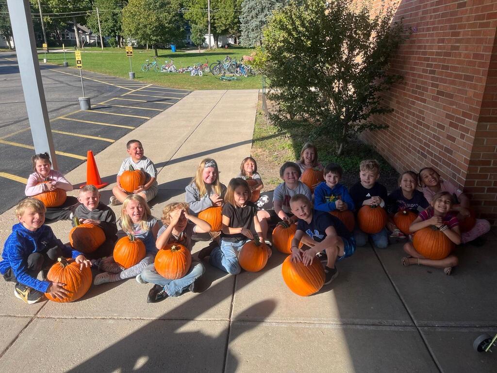 students sitting outside with their pumpkins