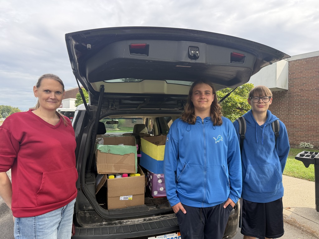 teacher and student posing with food boxes loaded in car