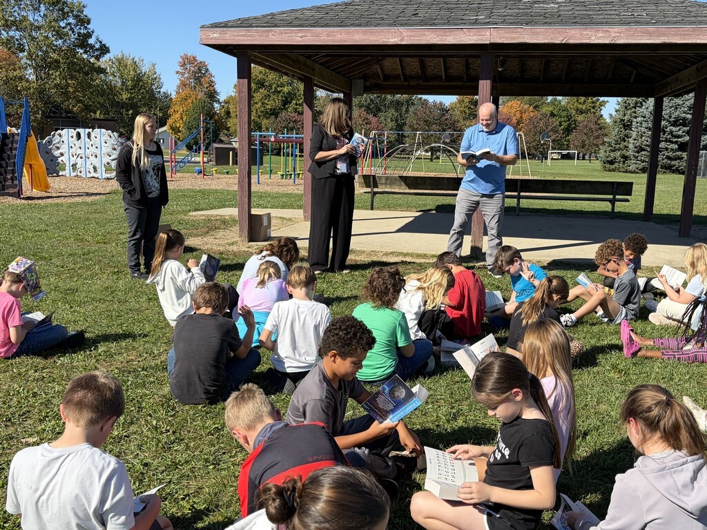 adults giving 3rd grade students dictionaries