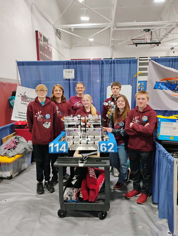 group of robotics students standing behind the robot they made