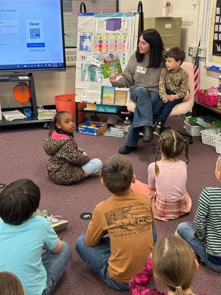 volunteer readers reading a book to students