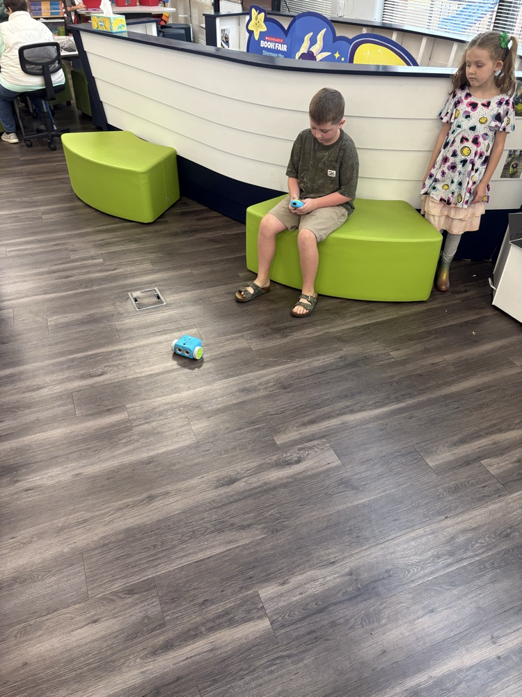 Students used a remote to code a new robot in the library. 