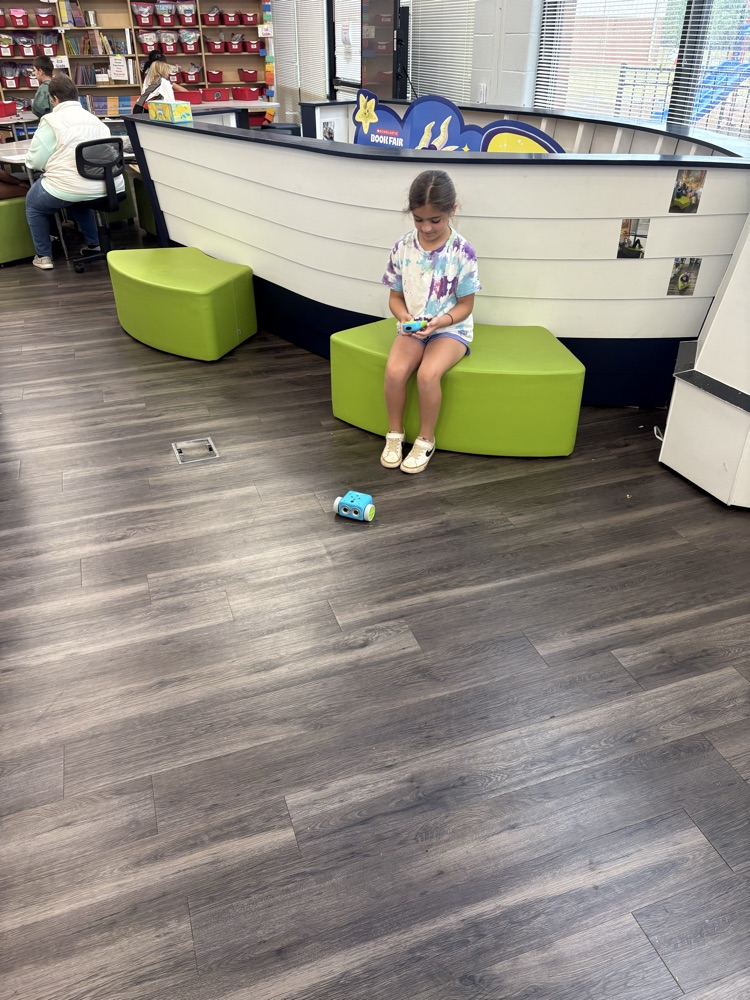 Students used a remote to code a new robot in the library. 