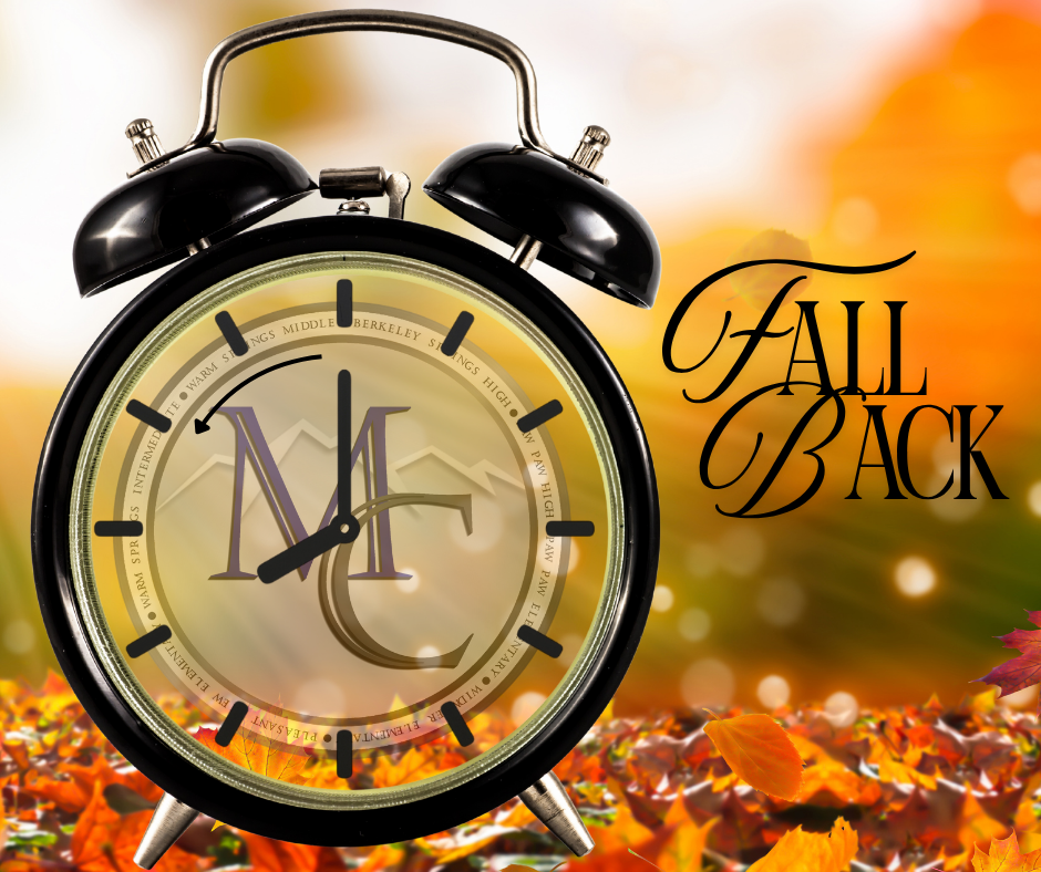 Clock with MCS logo and text “Fall Back” surrounded by autumn leaves.