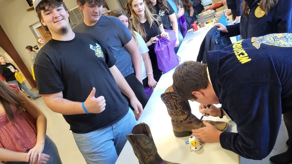 Chris getting his boots signed by FFA State Officers