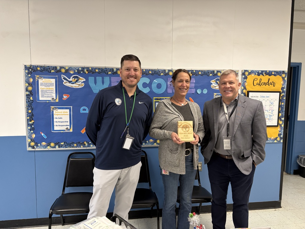 Three people standing in front of a welcome board holding an award.