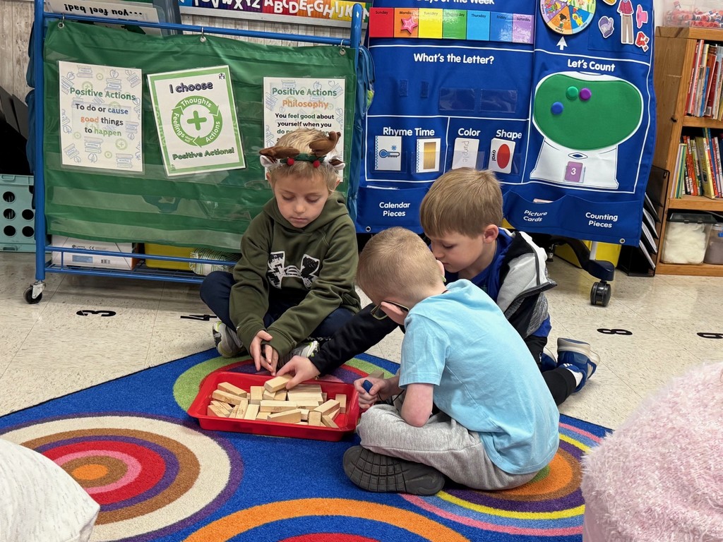 Students are sitting on the floor playing a game of Jenga.