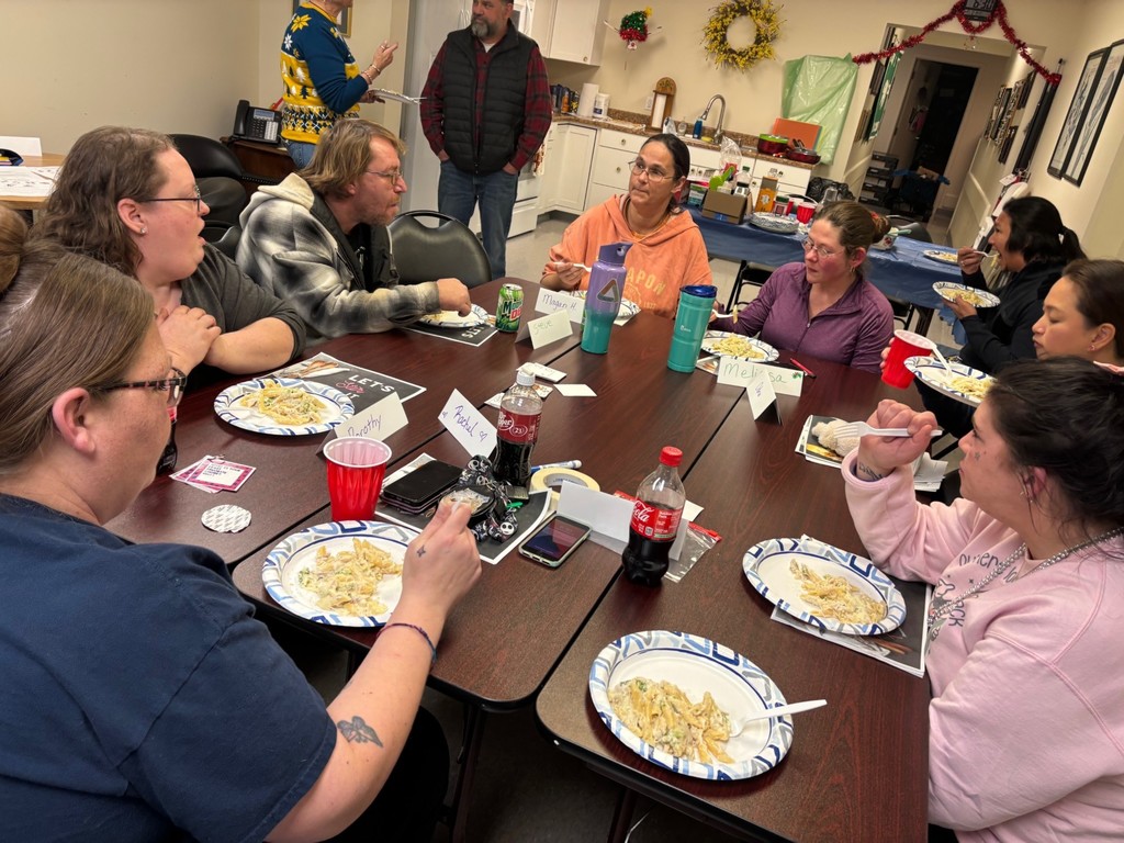 8 parents are sitting around the table, eating the chicken alfredo we prepared in class.