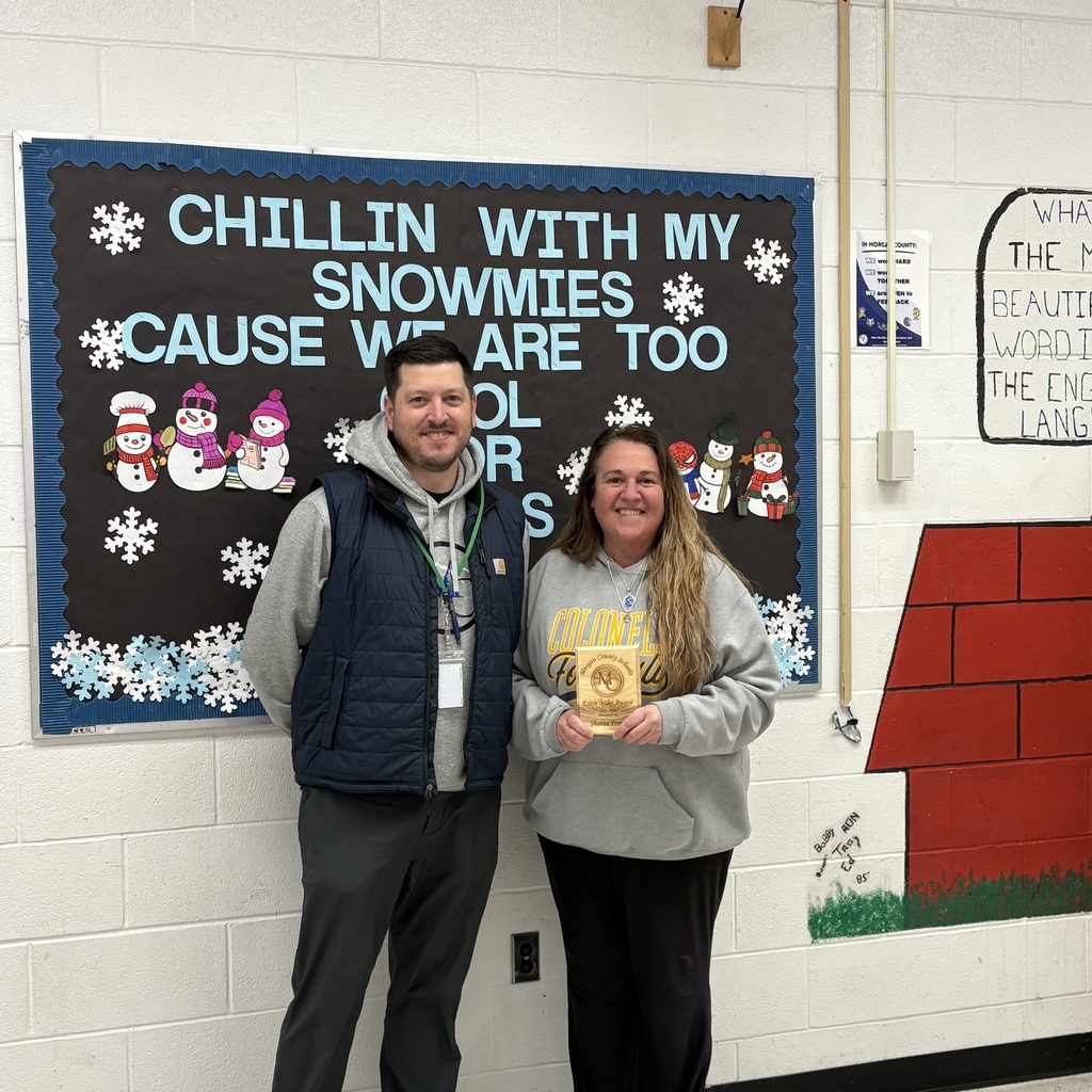 A staff member holding an award with the Assistant Superintendent.