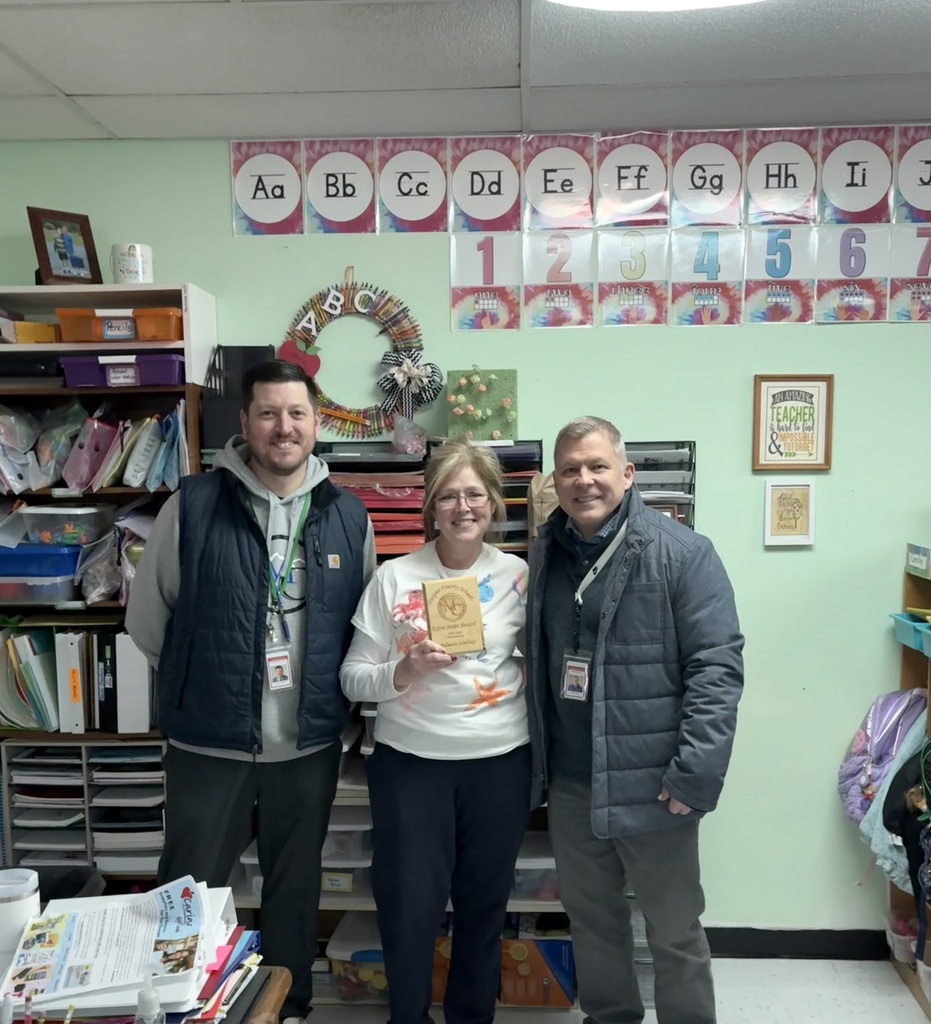 A staff member holding an award with the Superintendent and Assistant Superintendent.