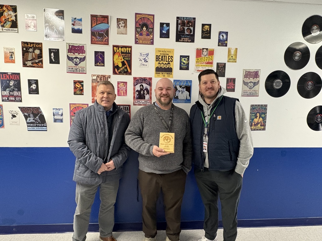 A staff member holding an award with the Superintendent and Assistant Superintendent.