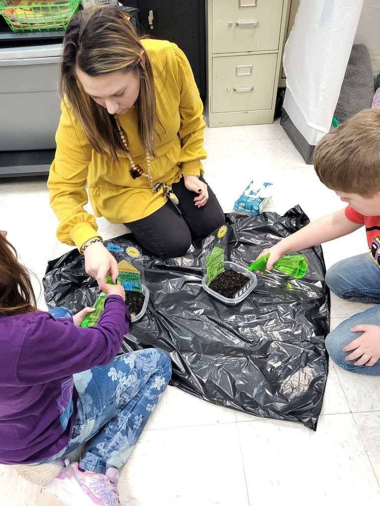 teacher helping students plant grass seeds