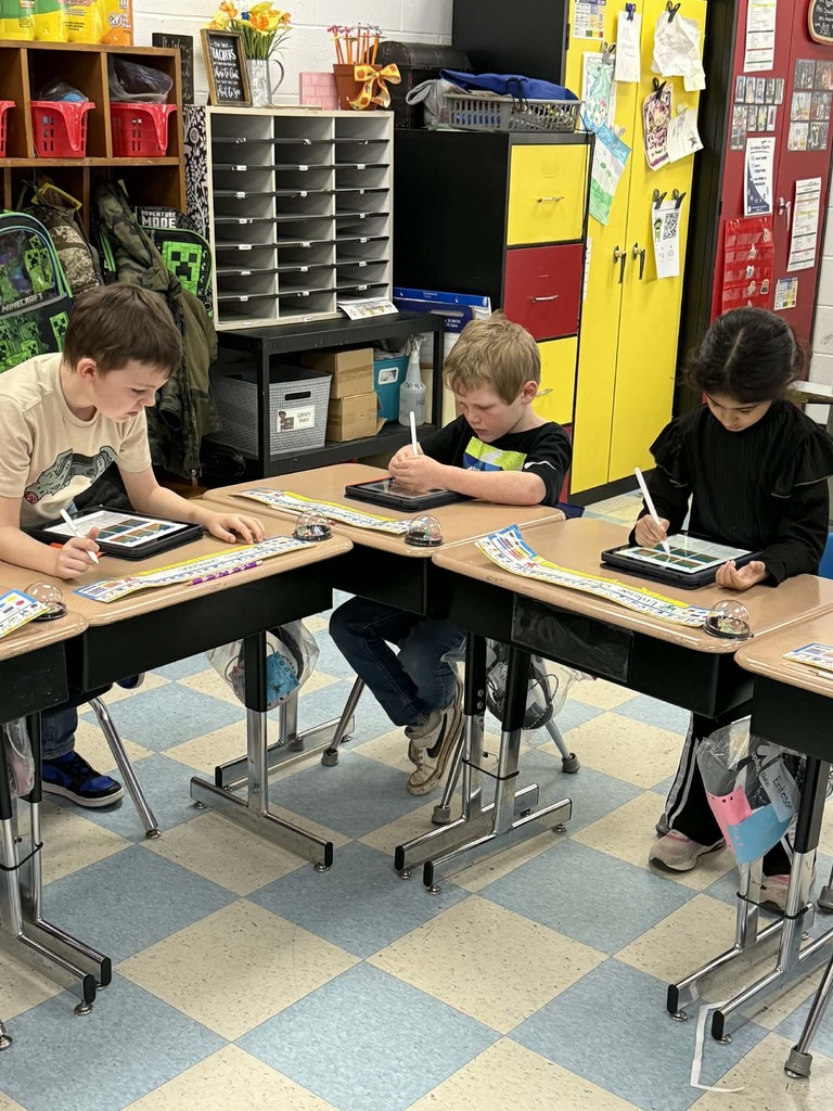 students sitting at desks using tables and pens