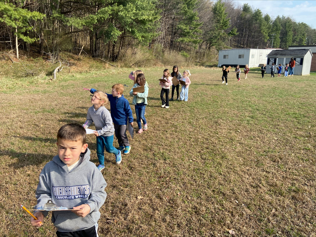 Students walking in a line through a field.
