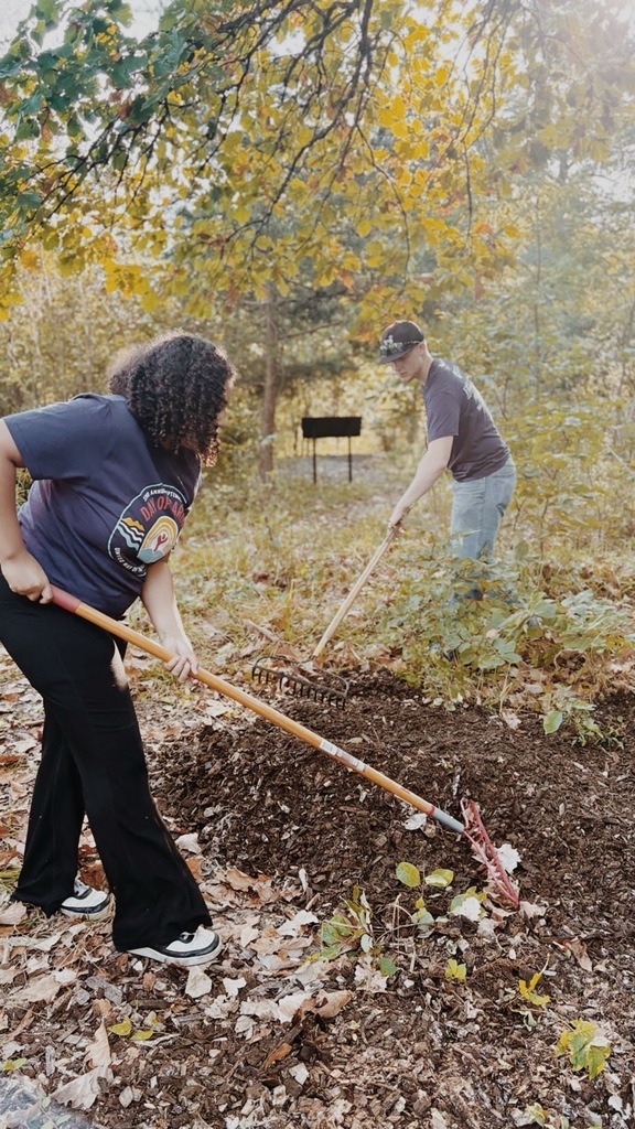 Two students spread mulch over wooded floors