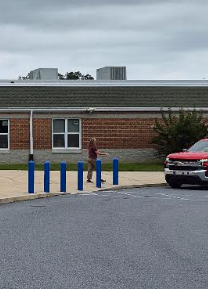 Staff member distributes Chromebooks outside the school.