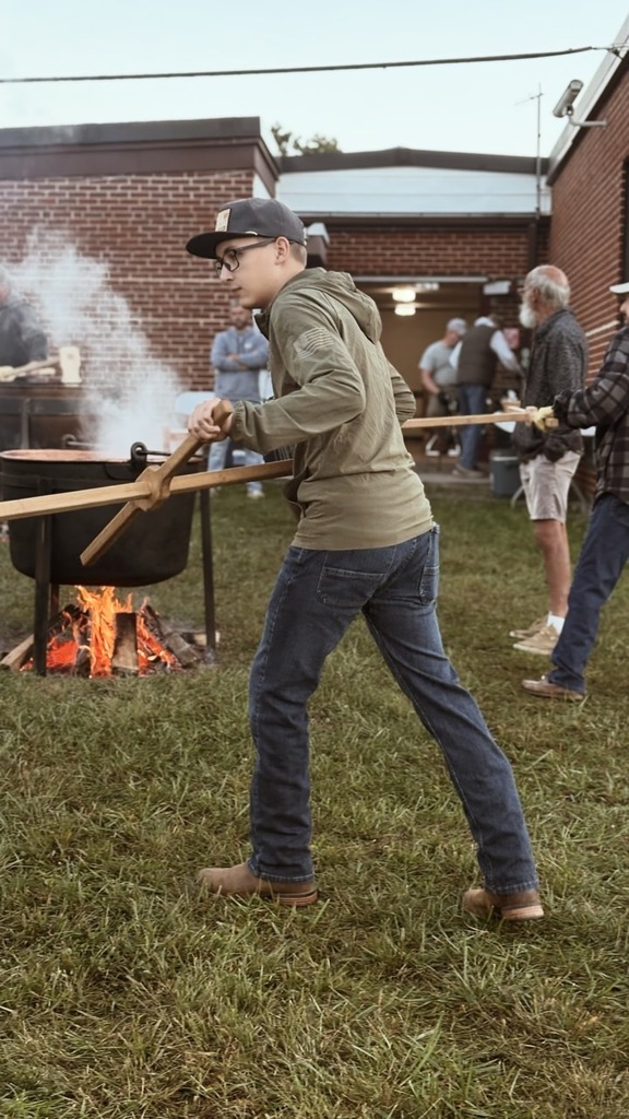 young member stirring apple butter