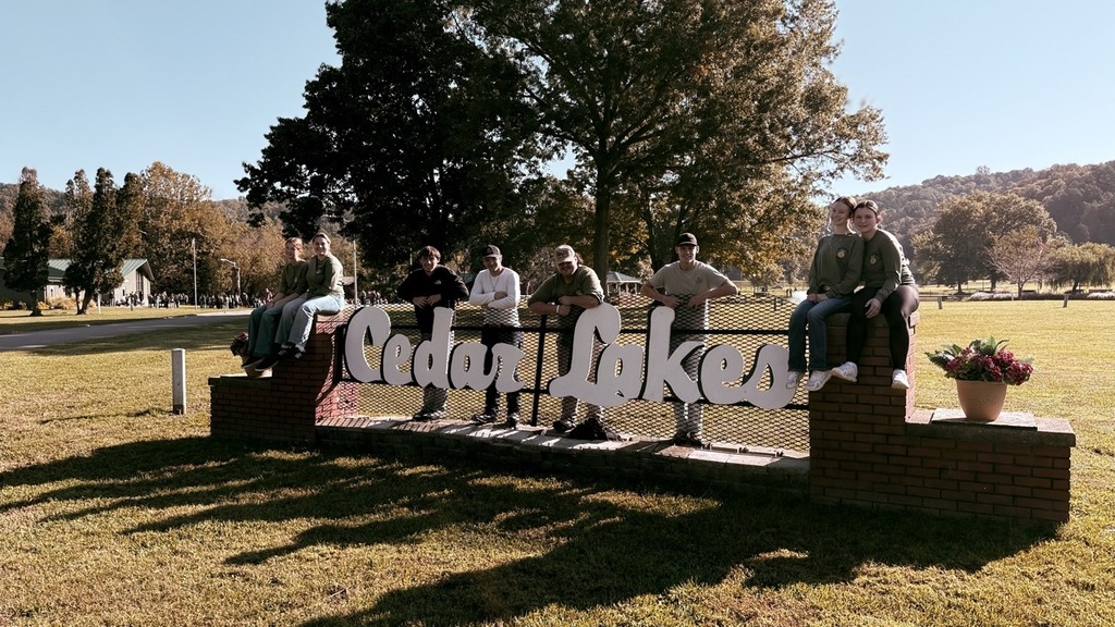 members pose for photo by a sign