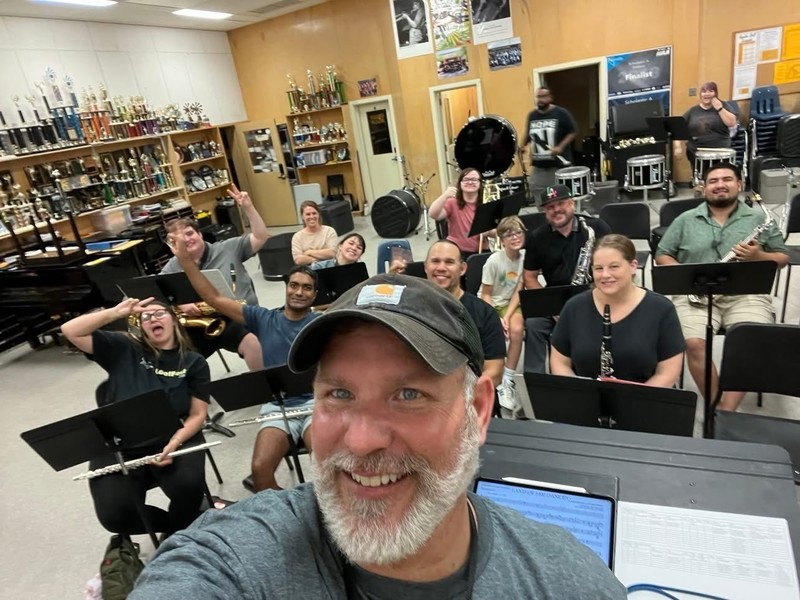 Bandleader Bill Barrett smiles for the camera alongside members of the Trojan Alumni Marching Band as they rehearse.