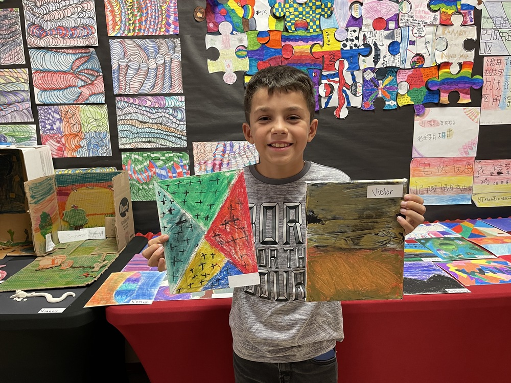 Student holds up 2 paintings