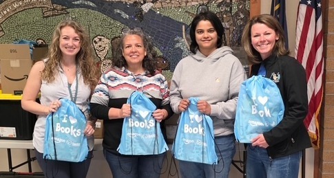 four female adults holding blue book bags