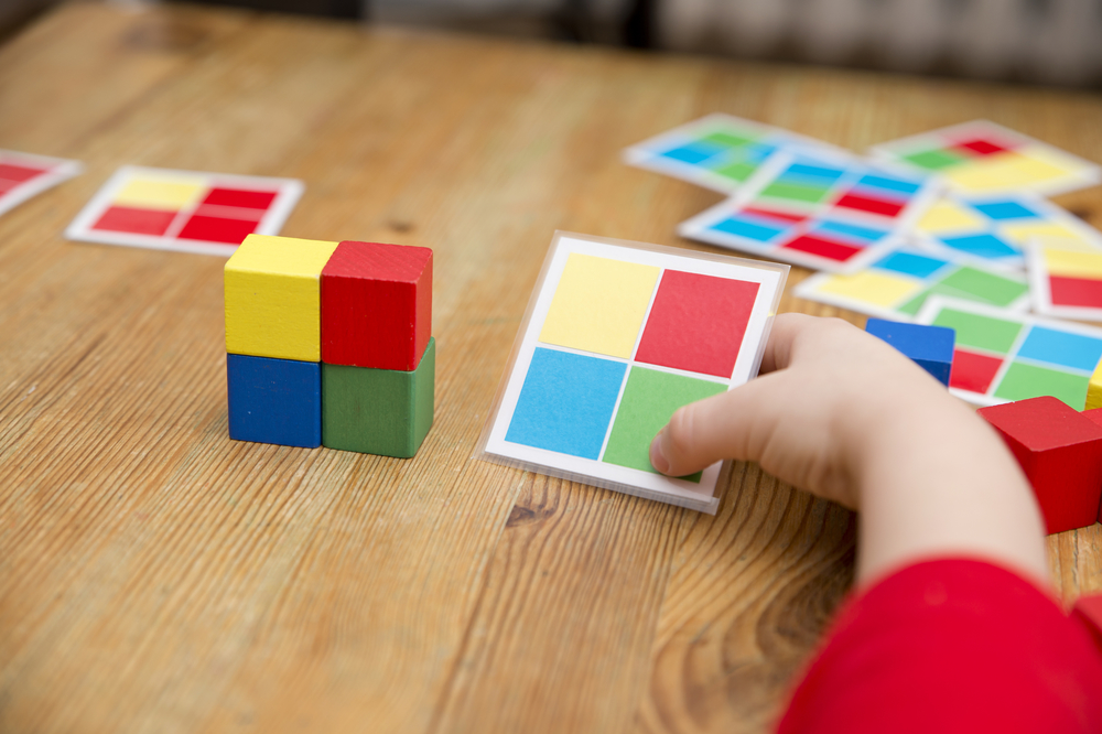 student builds blocks to match a laminated task card