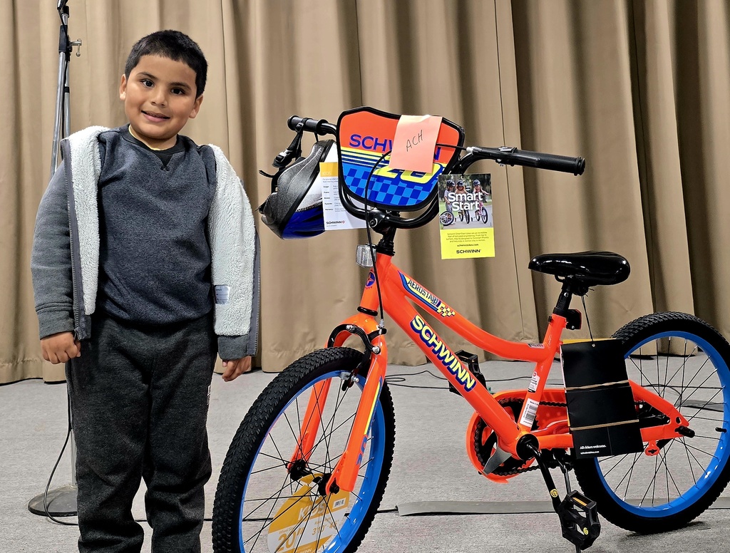 student Yael smiles next to his new bike