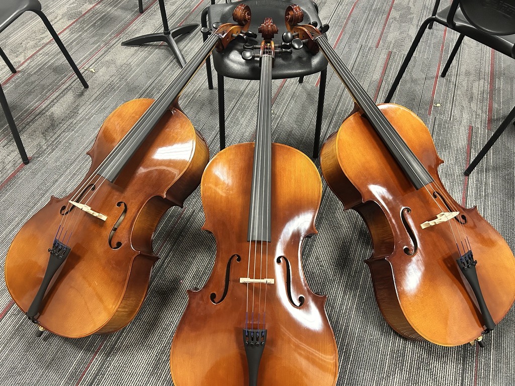 3 chellos  propped up against a chair