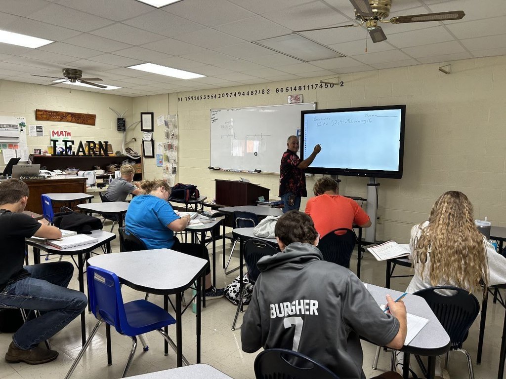 Teacher with students pointing at board