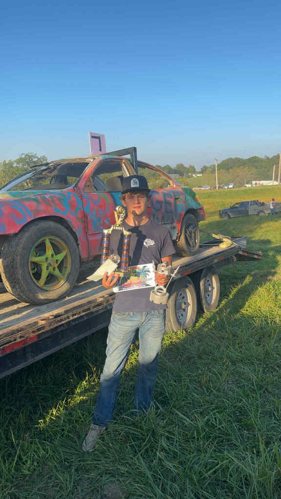 Ryder Shondel standing by his 2025 Appanoose County Redneck Rally car holding his trophy for 1st place in the Youth Division.