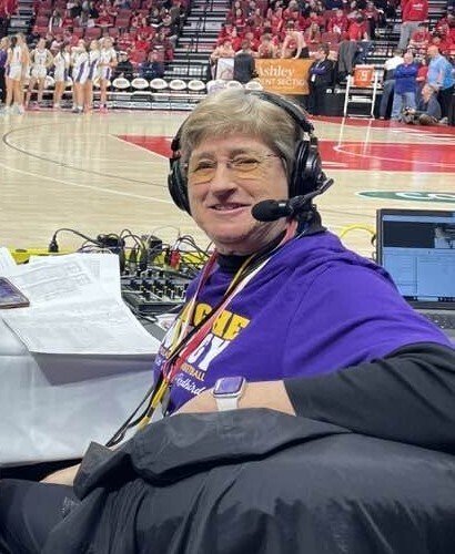 Photo of Jan Bowers with a radio headset on while calling a Toppers state basketball championship game