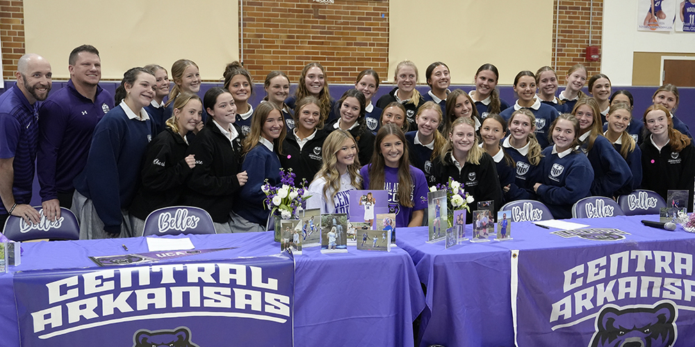 student athletes sitting at table surrounded by teammates