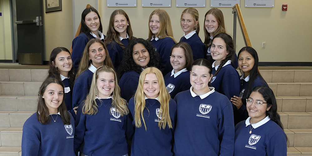 large group of female students in school uniform standing on steps in school foyer