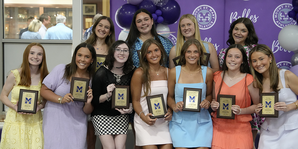 group of 11 female students holding award plaques and smiling at the camera